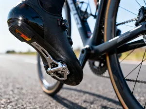 Dłonie precyzyjnie owijają korkową owijkę na kierownicy roweru szosowego w słonecznym warsztacie.